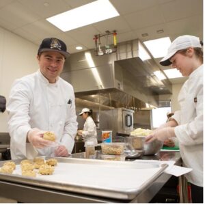 A couple of chefs preparing food in a kitchen