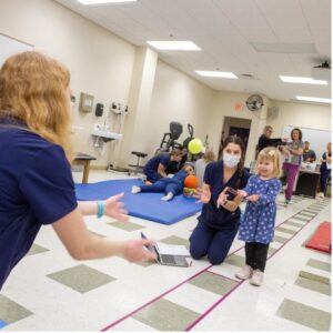 Two nurses throwing a ball with a little girl.